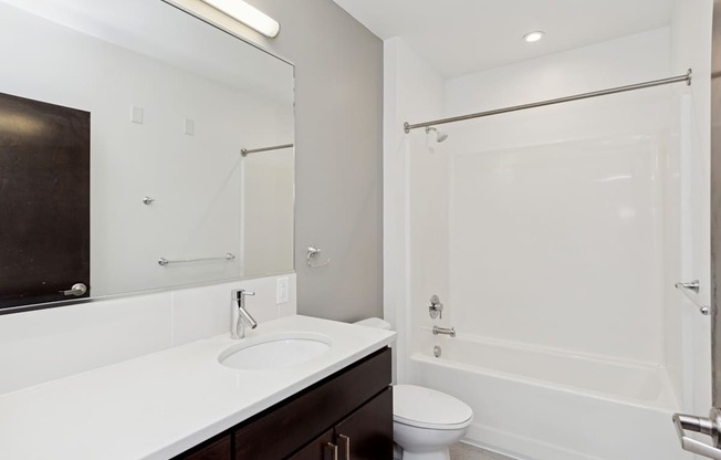 A white sink in a bathroom with a toilet and a shower.