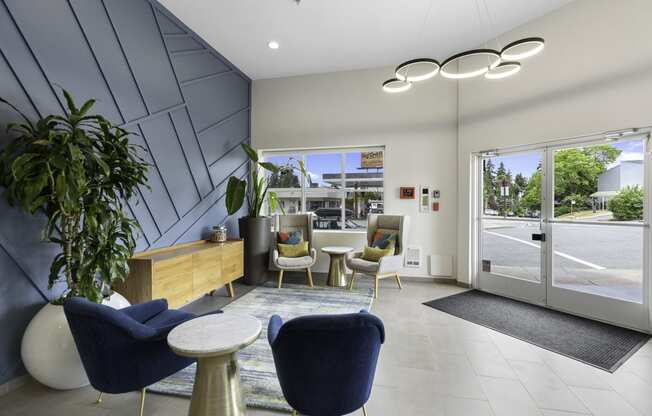 Lobby Area with blue chairs, textured dark blue accent wall, and a wooden desk with a plant in the corner at Arabella Apartment Homes, Shoreline