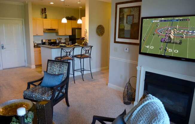 A living room with a fireplace and a television showing a football game.
