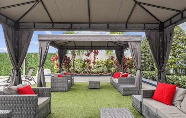 a lounge area with couches and chairs under a gazebo