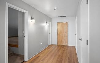 A hallway with a wooden floor and white walls.