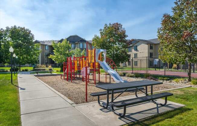 a playground and picnic table on a sidewalk in a park