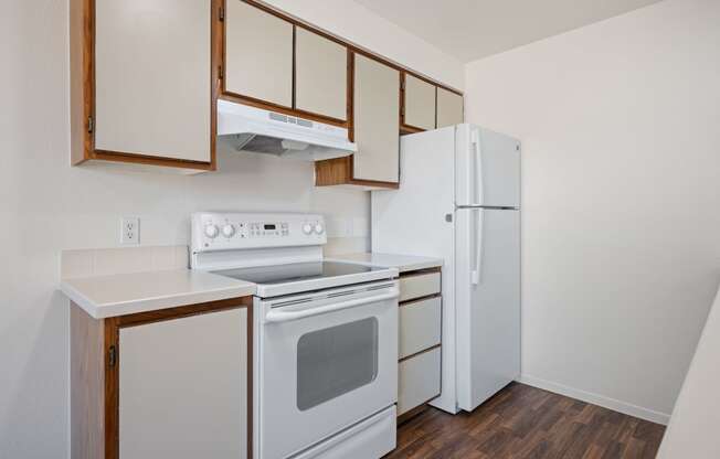a kitchen with white appliances and wood flooring and a refrigerator