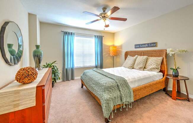 A bedroom with a bed, a ceiling fan, and a mirror on the wall.