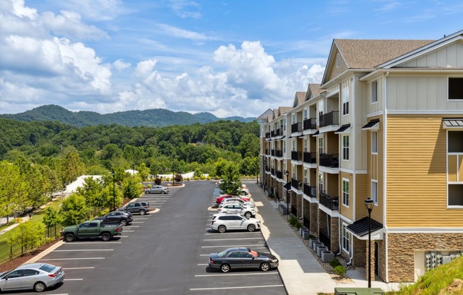 an apartment complex with a parking lot and mountains in the background