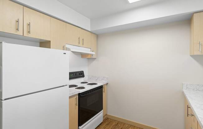 a kitchen with plank wood-style floors and white appliances at Guinevere Apartment Homes, Washington