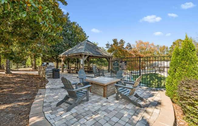 A gazebo is surrounded by chairs and a table in a backyard.