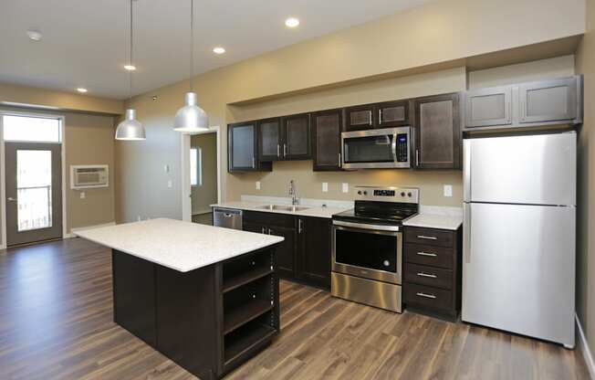 A kitchen with a refrigerator, oven, and microwave. Fargo, ND 29 West Apartments