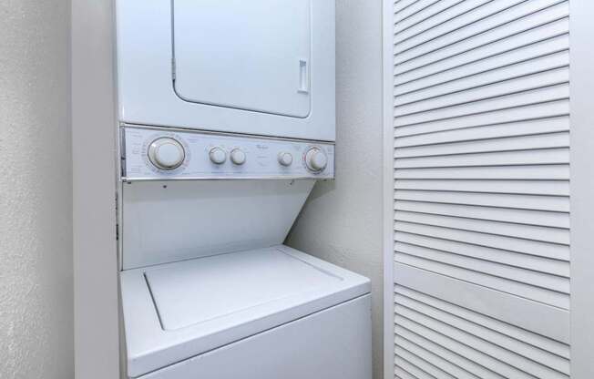 A white oven with a white door and white controls is next to a white wall with horizontal lines.