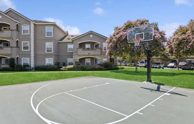 an outdoor basketball court in front of an apartment building