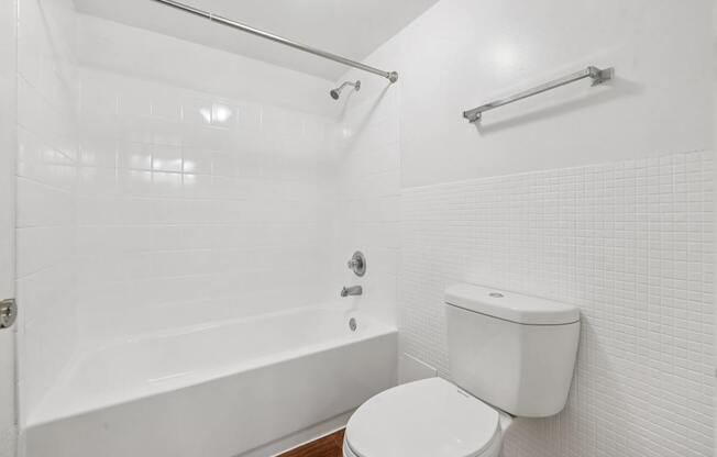 A white bathroom with a toilet, tub, and towel rack.