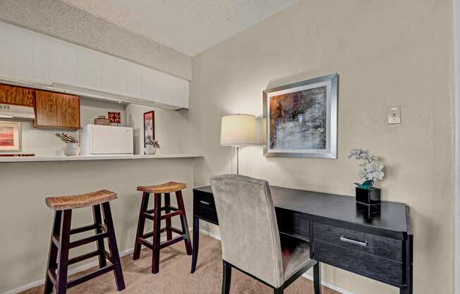 A versatile workspace here at Cypress Pointe with beige carpet, neutral walls, and a built-in desk area ideal for working from home. A breakfast bar with seating connects to the kitchen, creating a functional and comfortable space for daily tasks and casual dining.