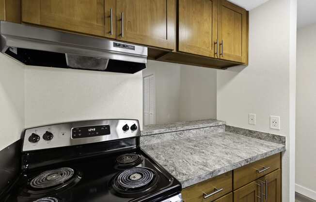 A Kitchen with Wood Cabinets and a Stove Top Oven at Park 210 Apartment Homes, Edmonds, WA