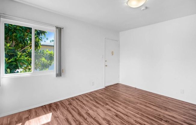 an empty living room with wood floors and a window