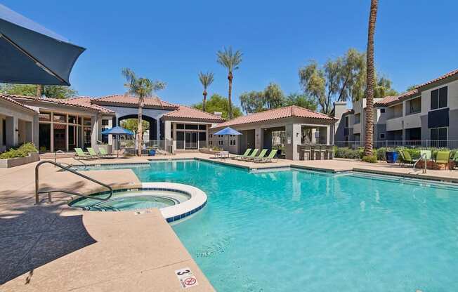 A swimming pool surrounded by palm trees and lounge chairs.