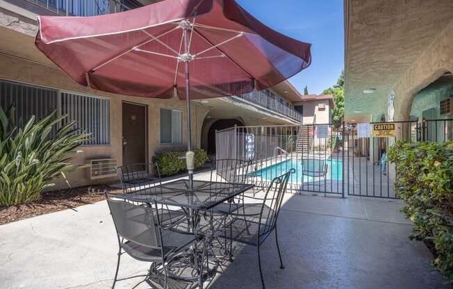 a patio with a table and chairs and a pool in the background