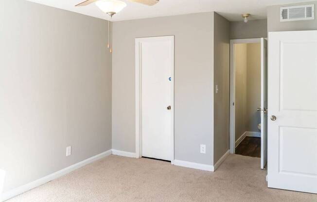 A room with a ceiling fan and two doors.