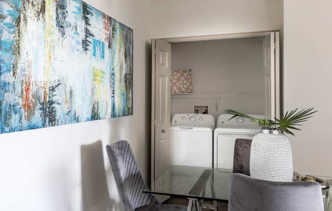 a dining room with a table and chairs and a painting on the wall