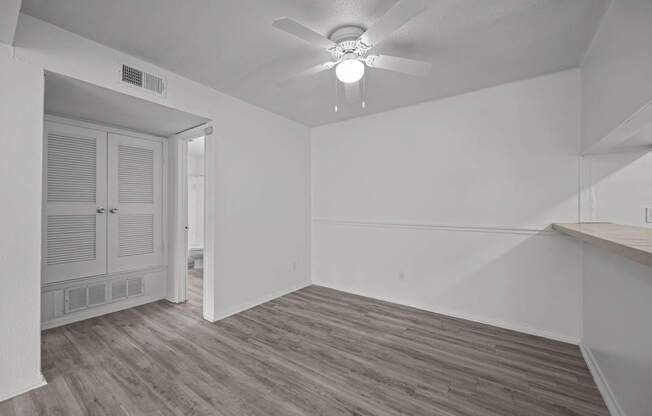 A room with a ceiling fan and wooden flooring.