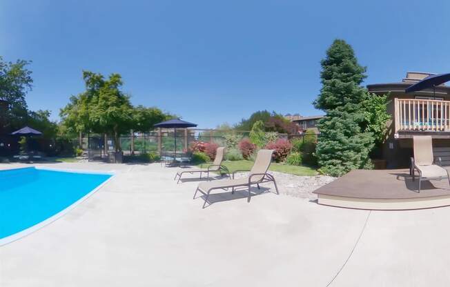 a backyard with a pool and patio with chairs and umbrellas at Lincoln Village Apartments, Spokane