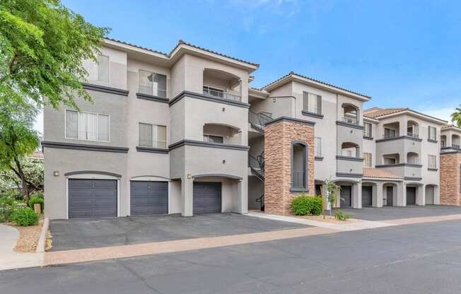 a street view of an apartment building with garage doors