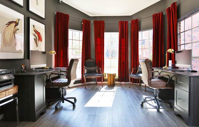 A business center with computers and red curtains at The Inverness Apartments in Houston, TX