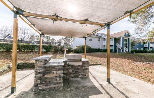 a covered patio with a grill and a stone wall