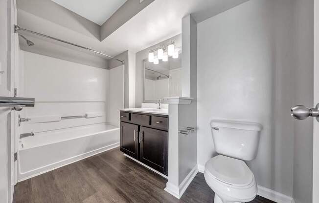 A white toilet sits in a bathroom with a wooden floor and white walls.