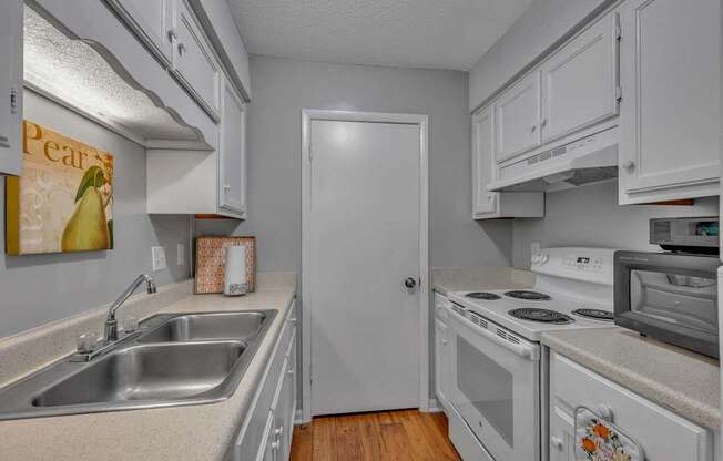 A kitchen with white cabinets and a white door.