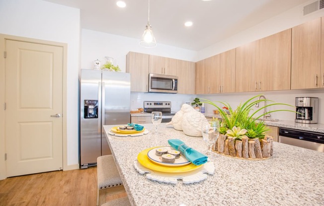 Pet-Friendly Apartments In Gilbert, AZ - Kitchen With Granite Countertops, Stainless Steel Appliances, Dishwasher, Tile Backsplashes, And Plank Flooring.