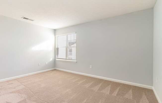 an empty room with a window and a carpeted floor