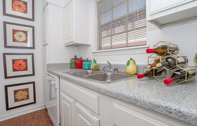 Furnished model apartment kitchen with double basin sink and white cabinets at Magnolia apartments in Shreveport, LA