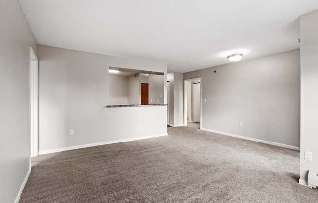 A spacious room with a carpeted floor and a door on the right side.