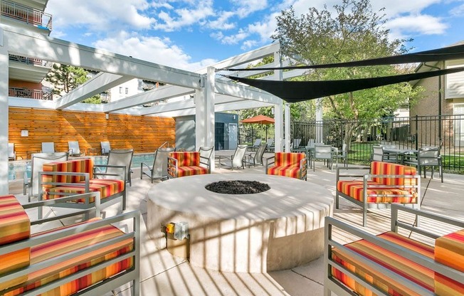A patio with a fire pit and chairs.