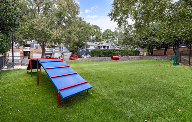 a blue and red trampoline in the middle of a grass field