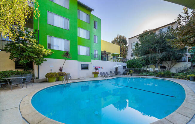 A swimming pool in front of a green and white building.