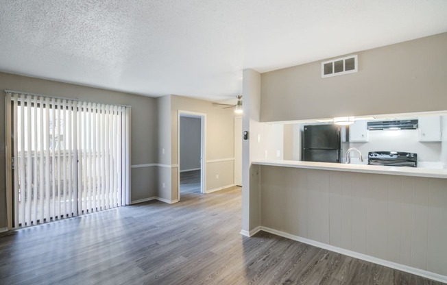 an open living room and kitchen with wood flooring and a large window