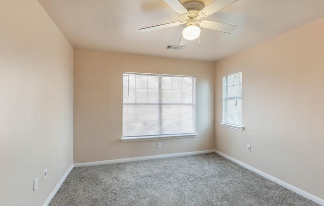 Bedroom with wall to wall carpet, ceiling fan, and windows