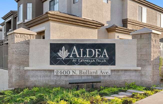 A sign for Aldea at Estrella Falls stands in front of a building.