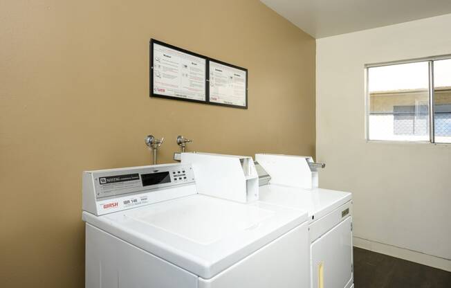 a laundry room with two washing machines and a window