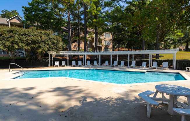 A pool with a white canopy and a picnic table.