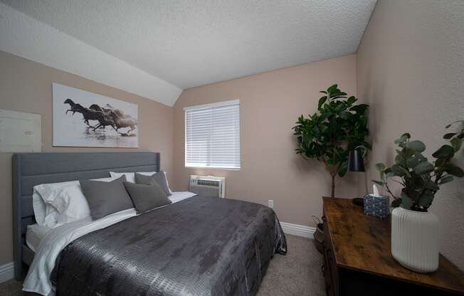 Bedroom in model unit with berber carpet and custom window blinds at the Atrium Apartments in San Diego, California.