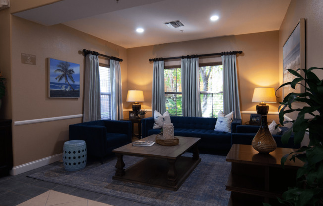 A living room with a blue couch, a wooden coffee table, and a painting of a beach scene on the wall.