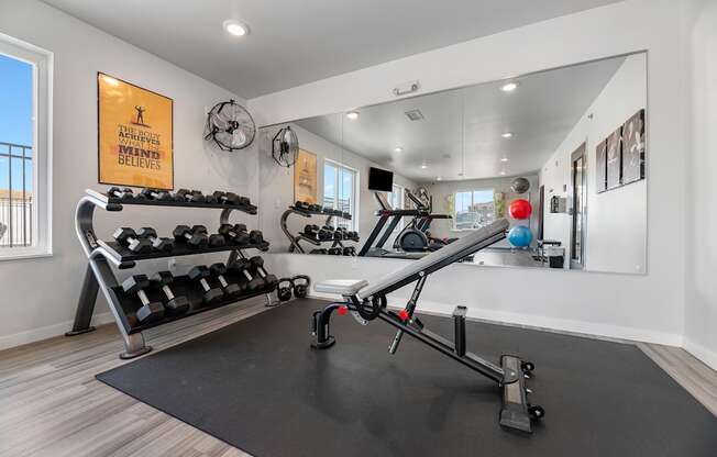 a home gym with weights and mirrors and a large mirror on the wall