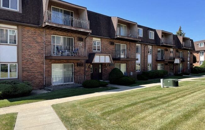 a brick apartment building with balconies and a lawn