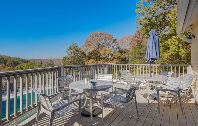 a patio with tables and chairs on a deck overlooking a swimming pool