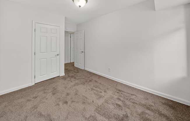 A room with carpeted floor and two doors.