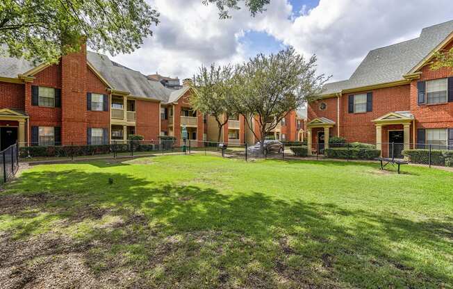 A grassy area in front of a row of red brick houses.