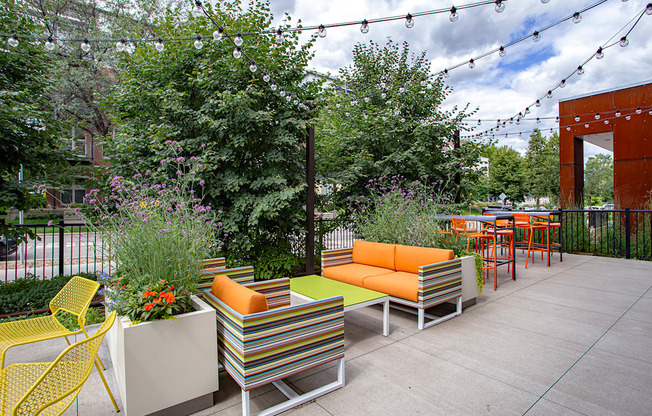 A patio with a yellow chair and a striped couch.