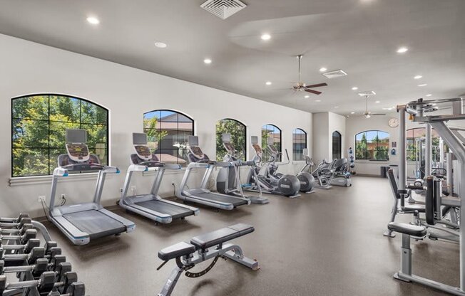 a gym with cardio equipment and windows